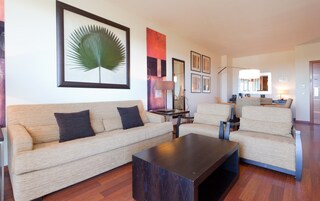 Een moderne woonkamer met een bank, fauteuils, een salontafel en kunst aan de muren.