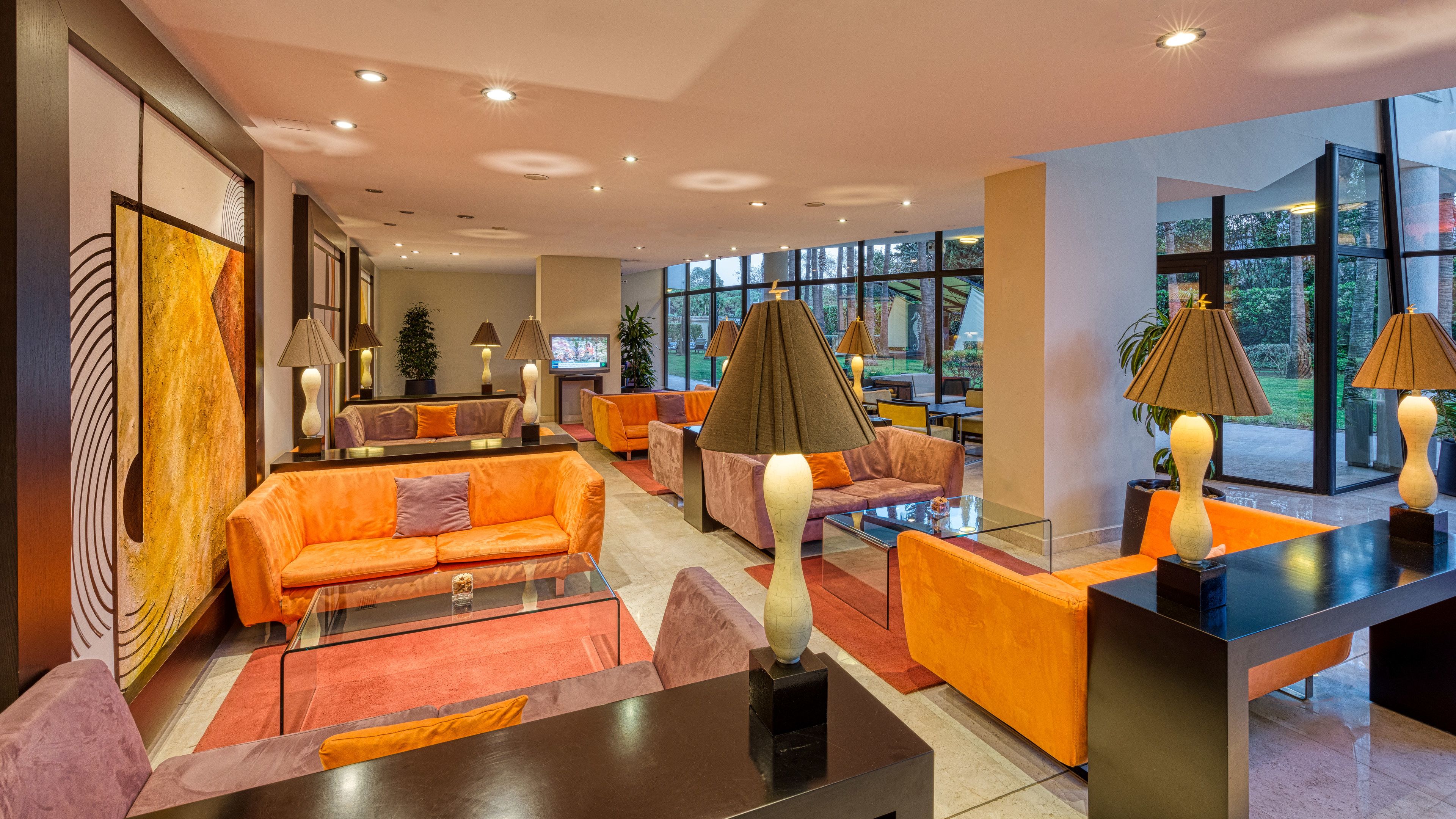 A modern lobby with orange sofas, a glass coffee table, and a reception desk.
