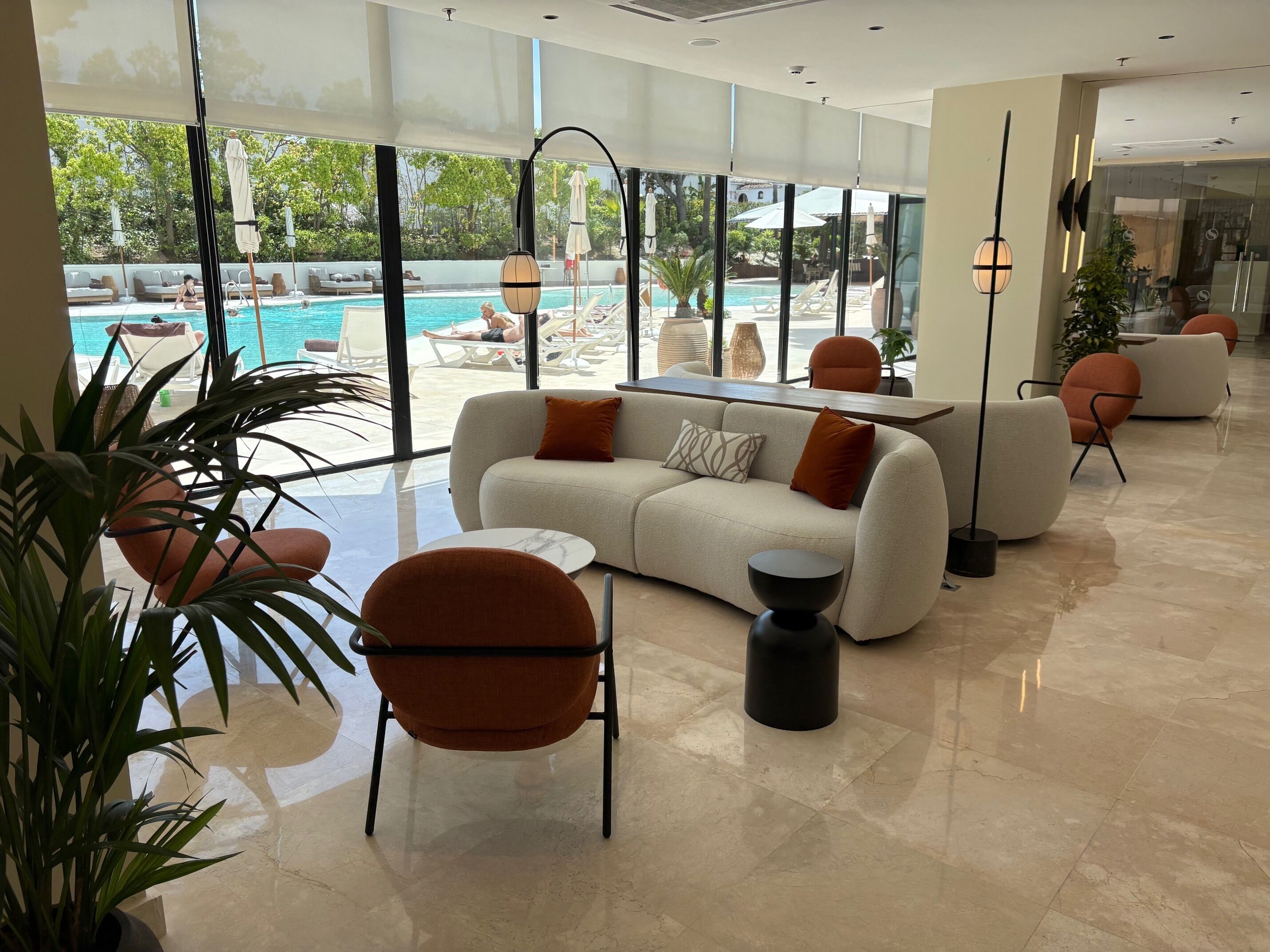 A modern lounge area with a sofa, chairs, and a pool view.