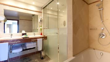 Un baño moderno con ducha envuelta en vidrio, una bañera y un tocador con espejo y toallero.