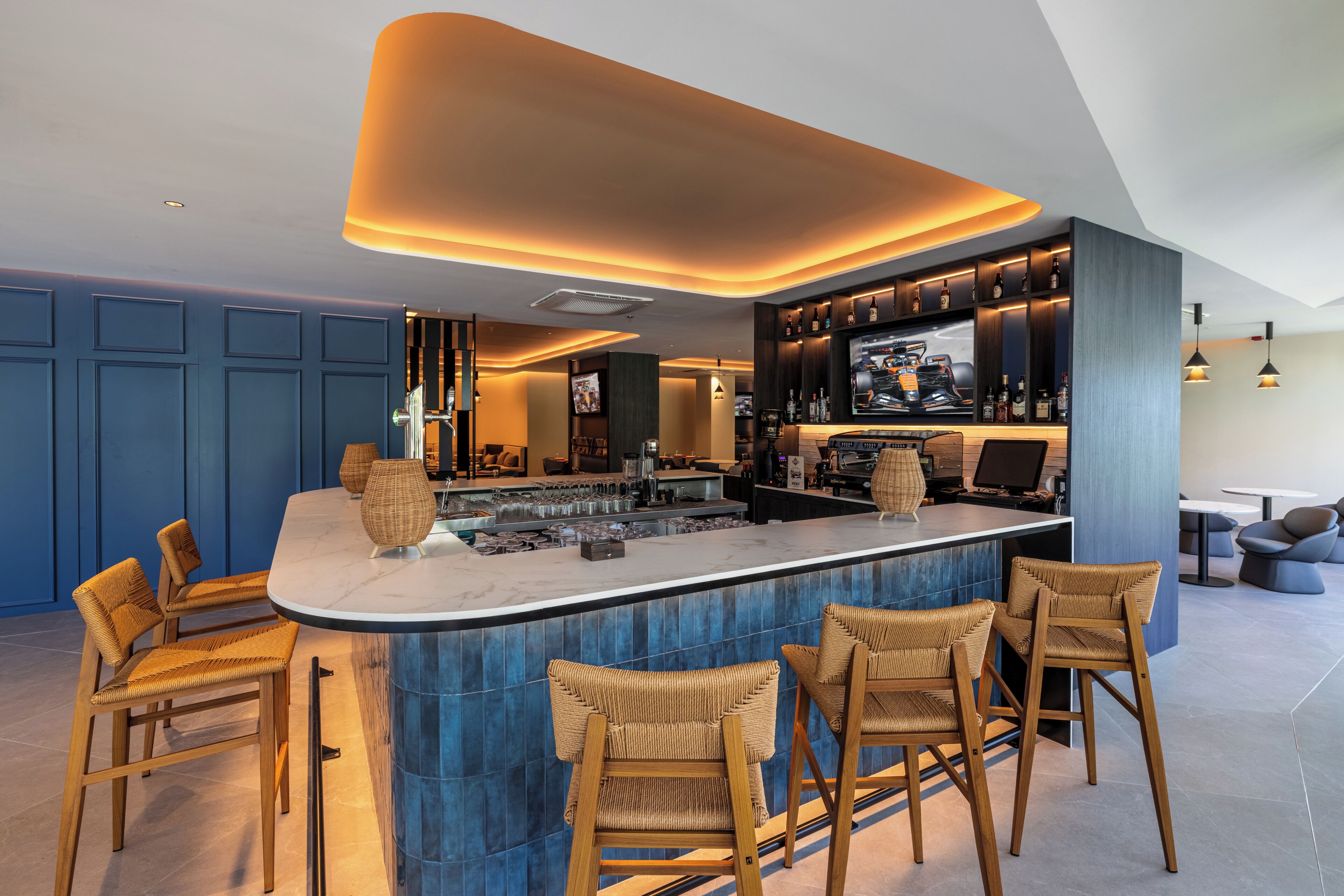 A modern bar area with a central island, bar stools, and a television screen.