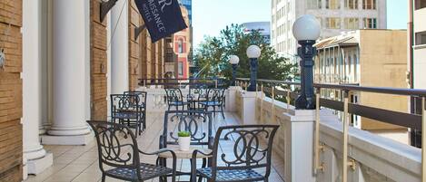 A rooftop terrace with outdoor seating, a flag, and a view of the cityscape.