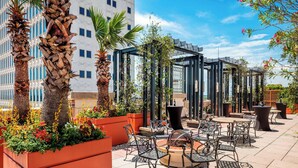 An outdoor patio area with seating arrangements, potted plants, and a pergola structure. - The Battle House Renaissance Mobile Hotel & Spa (Mobile)