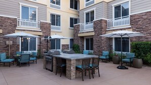 A patio area with a grill, outdoor seating, and umbrellas. - Homewood Suites by Hilton Agoura Hills (Agoura Hills)