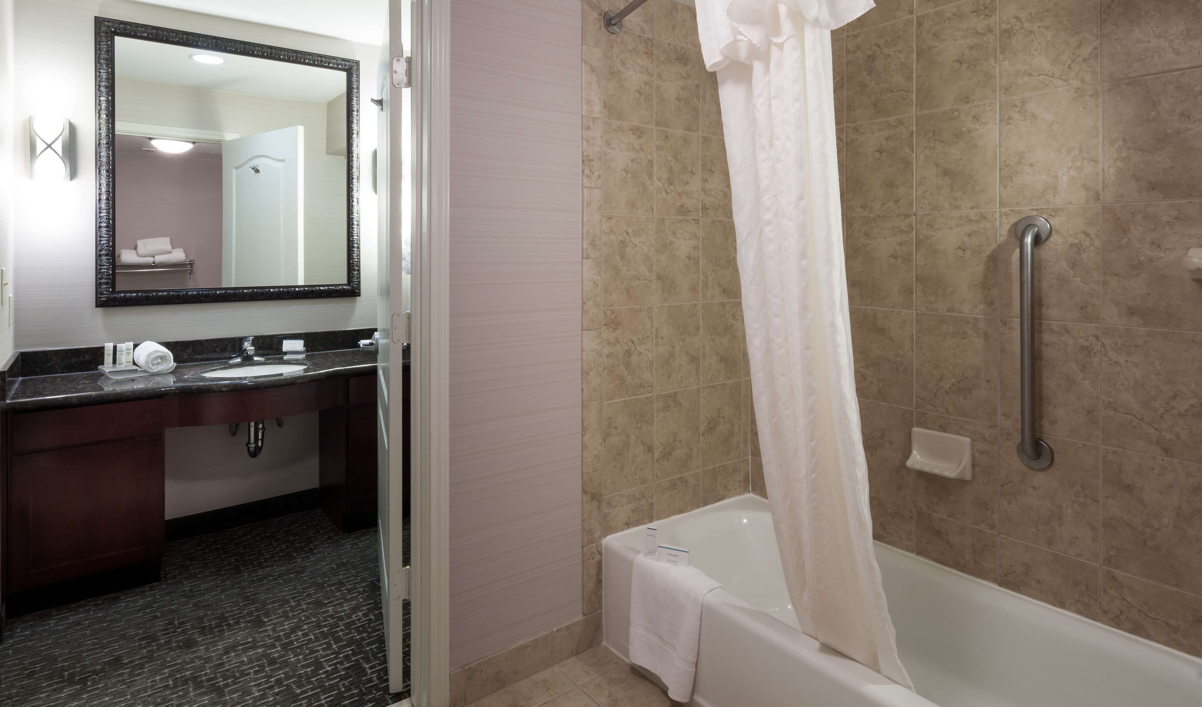 A bathroom with a sink, mirror, and shower area.