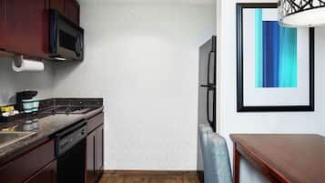 A kitchen with dark wooden cabinets, a stainless steel refrigerator, a microwave, and a coffee maker.