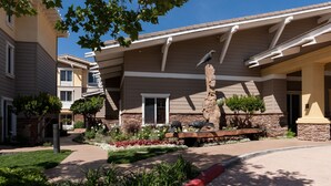 A residential building with a stone facade, a landscaped garden with various plants and flowers, and a bird sculpture on a pedestal. - Homewood Suites by Hilton Agoura Hills (Agoura Hills)