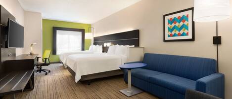 Una habitación de hotel con una cama, un sofá azul, un escritorio con una silla, un televisor y una lámpara.