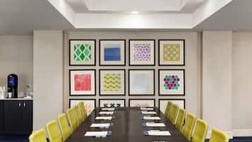 A conference room with a long table, yellow chairs, and framed artwork on the walls.