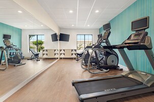 Un gimnasio con cintas de correr, bicicletas estáticas y máquinas de pesas.