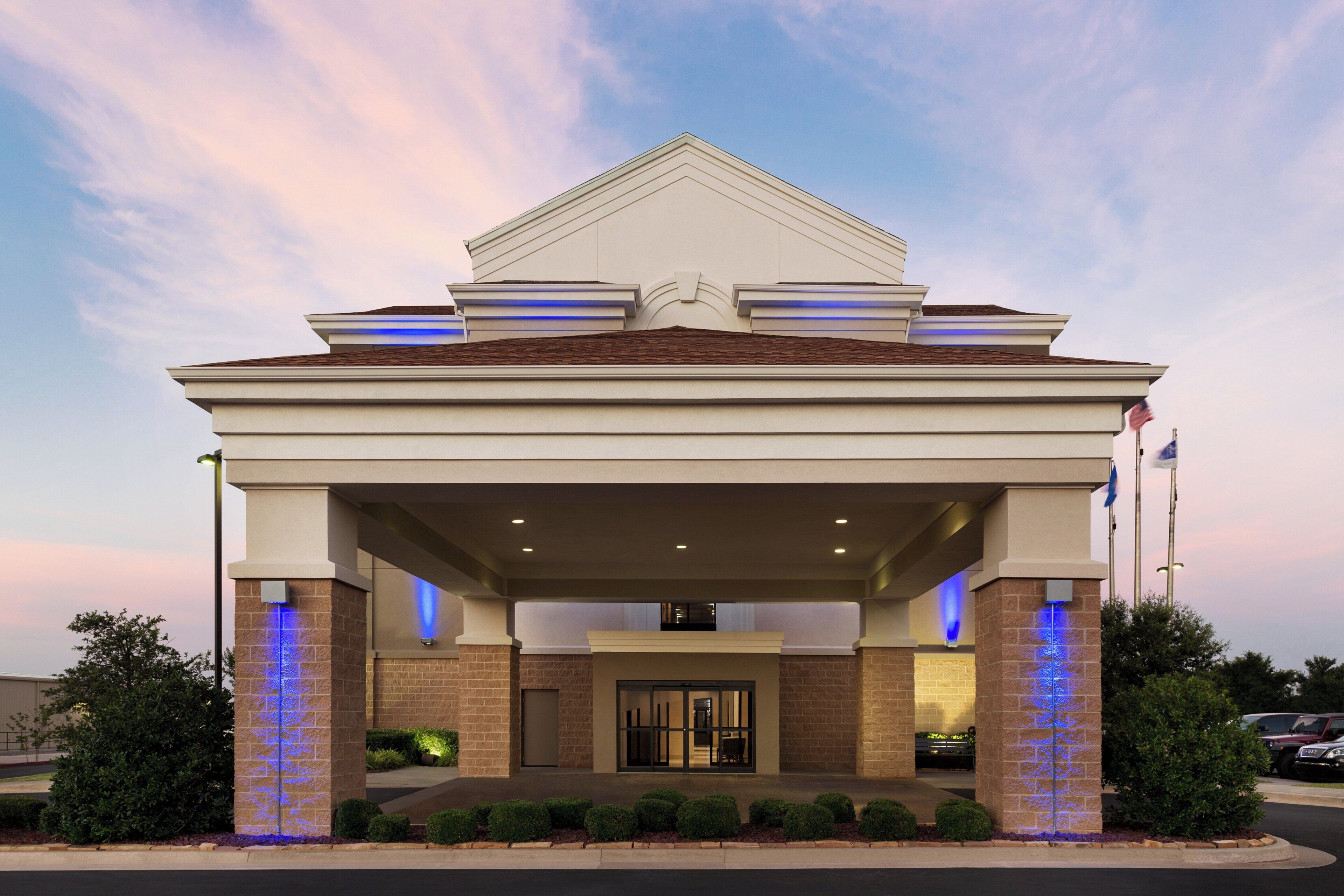 A hotel entrance with a covered walkway, a brick facade, and illuminated pillars.