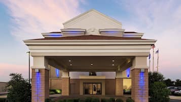 A hotel entrance with a covered walkway, a brick facade, and illuminated pillars.