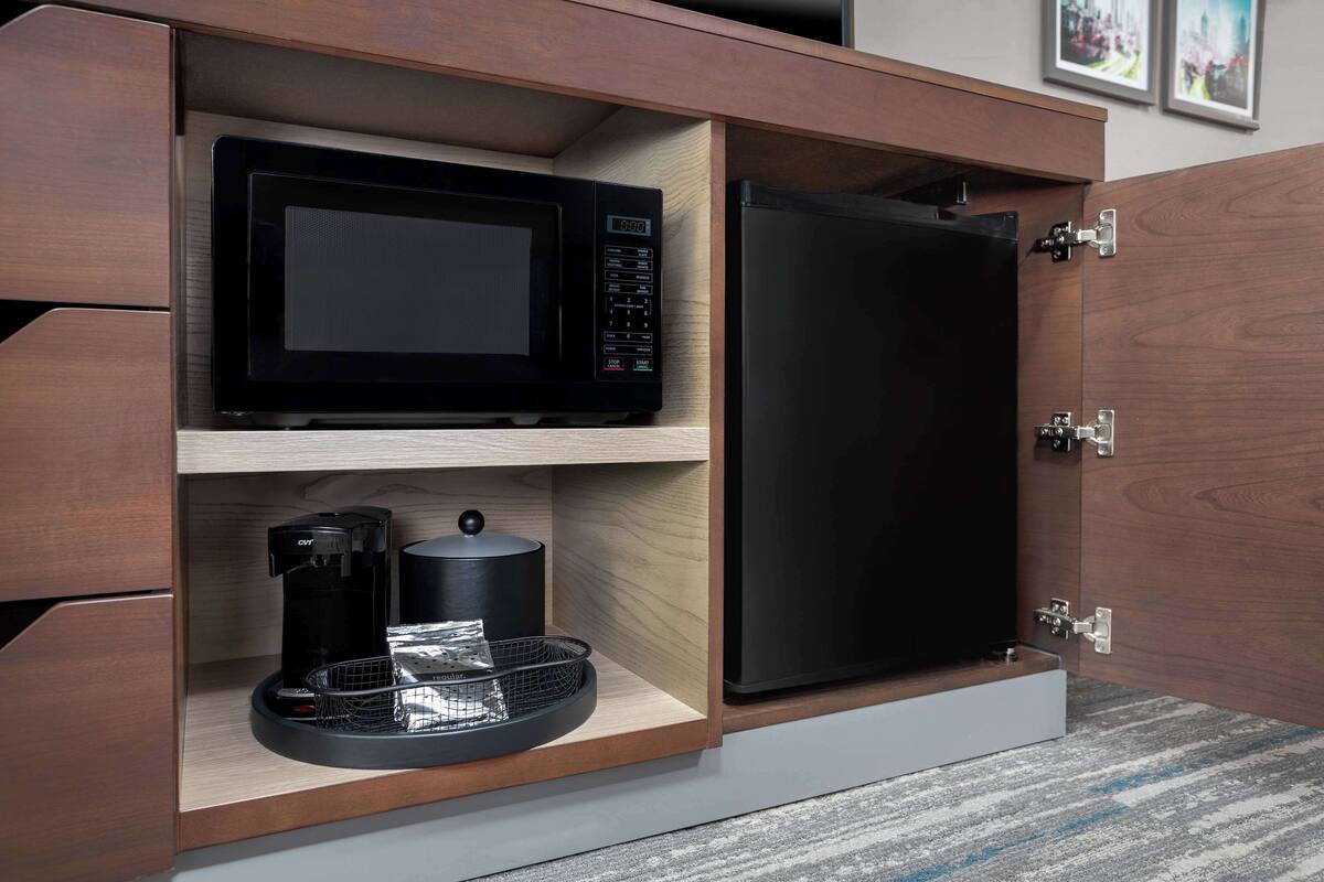 A kitchen with a microwave, coffee maker, and refrigerator built into a wooden cabinet.