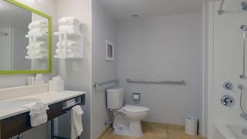 Un baño moderno con lavamanos, inodoro y ducha blancos. Hay toallas en el mostrador y un espejo con marco verde.