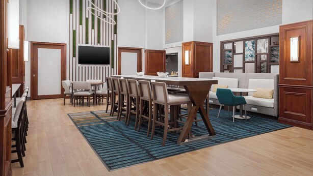 Eine moderne Hotelhalle mit Essbereich, einer Couch und einem Fernseher.