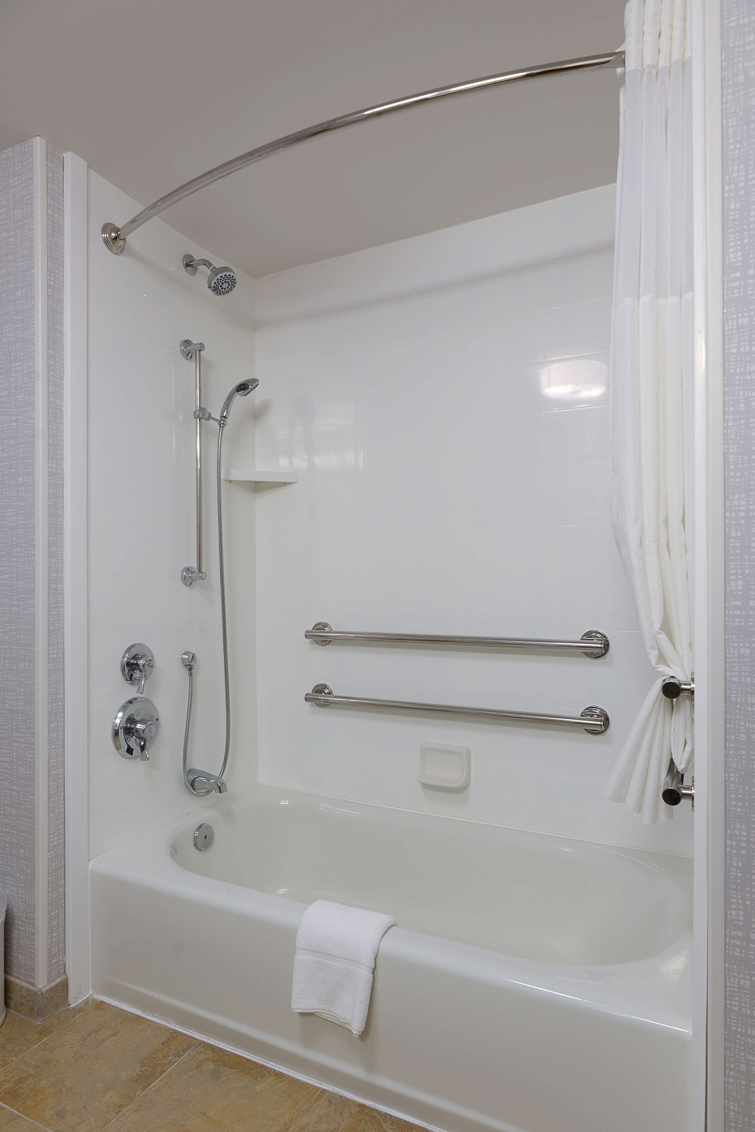 A modern bathroom with a walk-in bathtub, grab bars, and a showerhead.