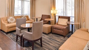Una habitación de hotel con sofá, sillones, una mesita y una lámpara.