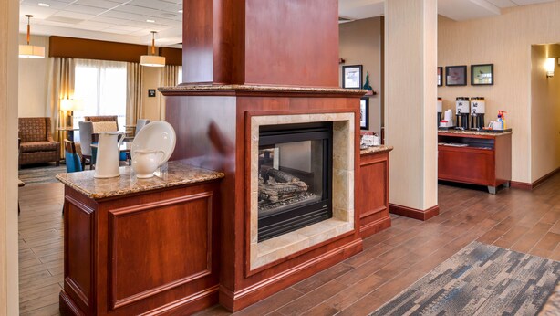 Un vestíbulo de hotel con chimenea, una estación de café y una zona de estar.