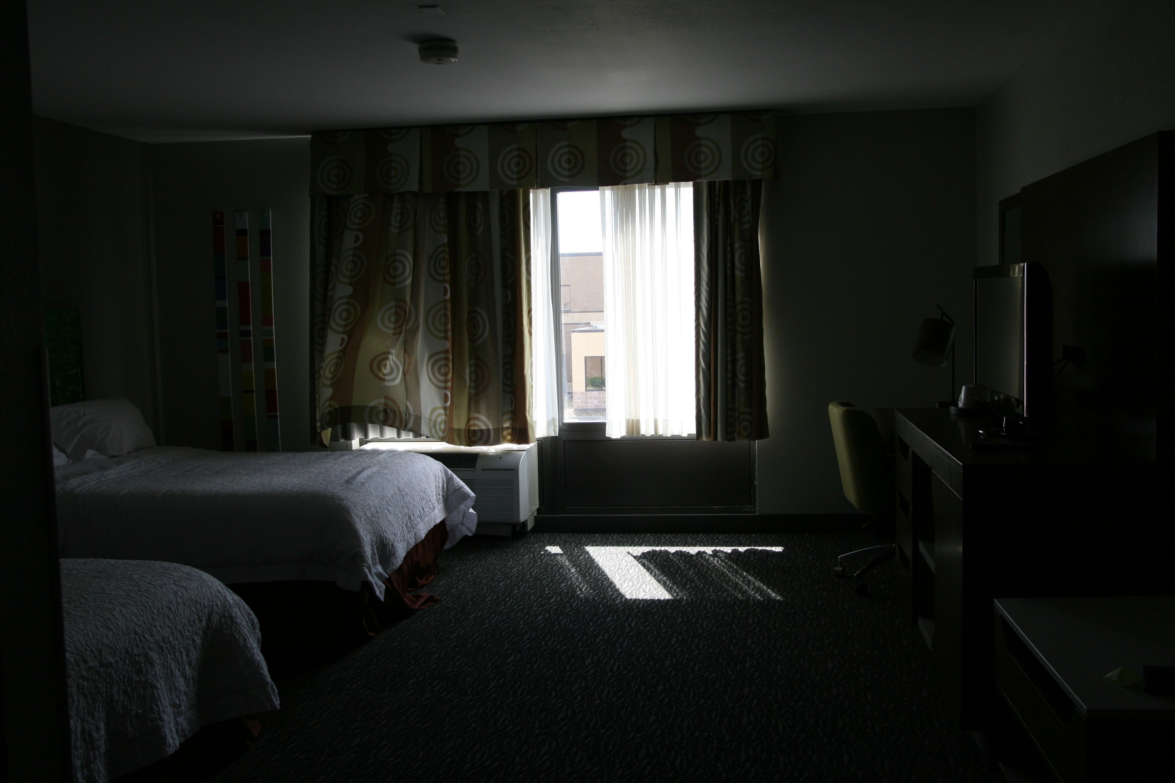 A hotel room with two beds, a desk, and a chair.