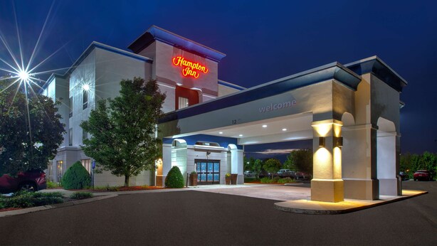 Un hotel Hampton Inn con una fachada moderna, un letrero de neón y una entrada acogedora.