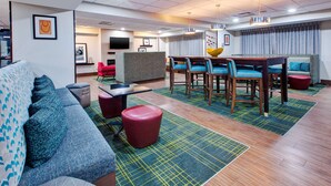 Un moderno vestíbulo de hotel con un sofá, sillas, una mesa de comedor y un televisor.