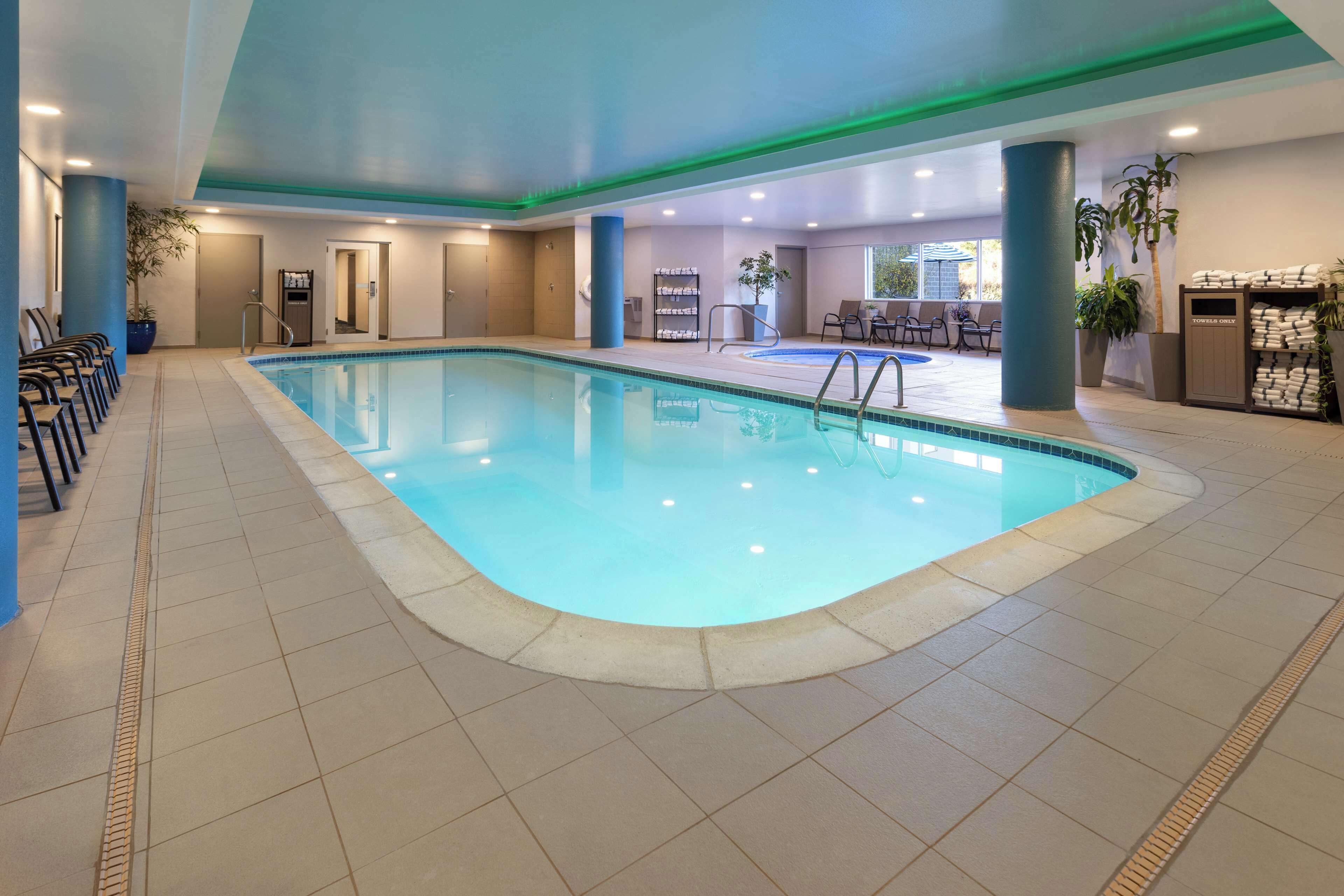 Una piscina interior con agua azul cristalina, rodeada de paredes y suelo de azulejos.