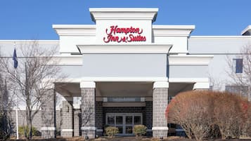 Welcome to Hampton Inn & Suites, featuring a modern entrance with a large glass door and bold signage.