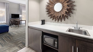 A modern kitchen with a built-in microwave, a sink, and a decorative wooden mirror. - Hampton Inn & Suites Wells-Ogunquit (Wells)