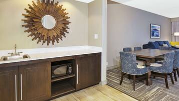 A modern kitchen with a built-in microwave, a sink, and a decorative sunburst mirror.