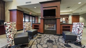 A lobby with a fireplace, seating area, and a television.