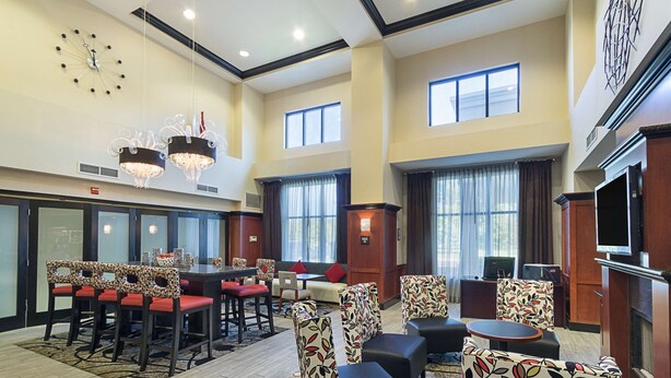 A spacious hotel lobby with a high ceiling, multiple seating areas, and a large wall clock.