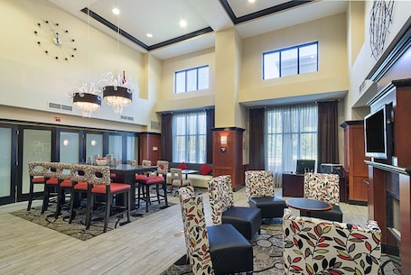 A spacious hotel lobby with a high ceiling, multiple seating areas, and a large wall clock.