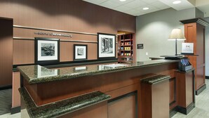 A reception desk with framed pictures, a welcome sign, a counter, and a lamp.