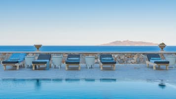 Una piscina techada, una piscina al aire libre, sombrillas