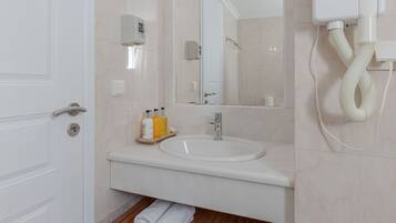 Un baño con lavamanos, espejo y toallero blancos.