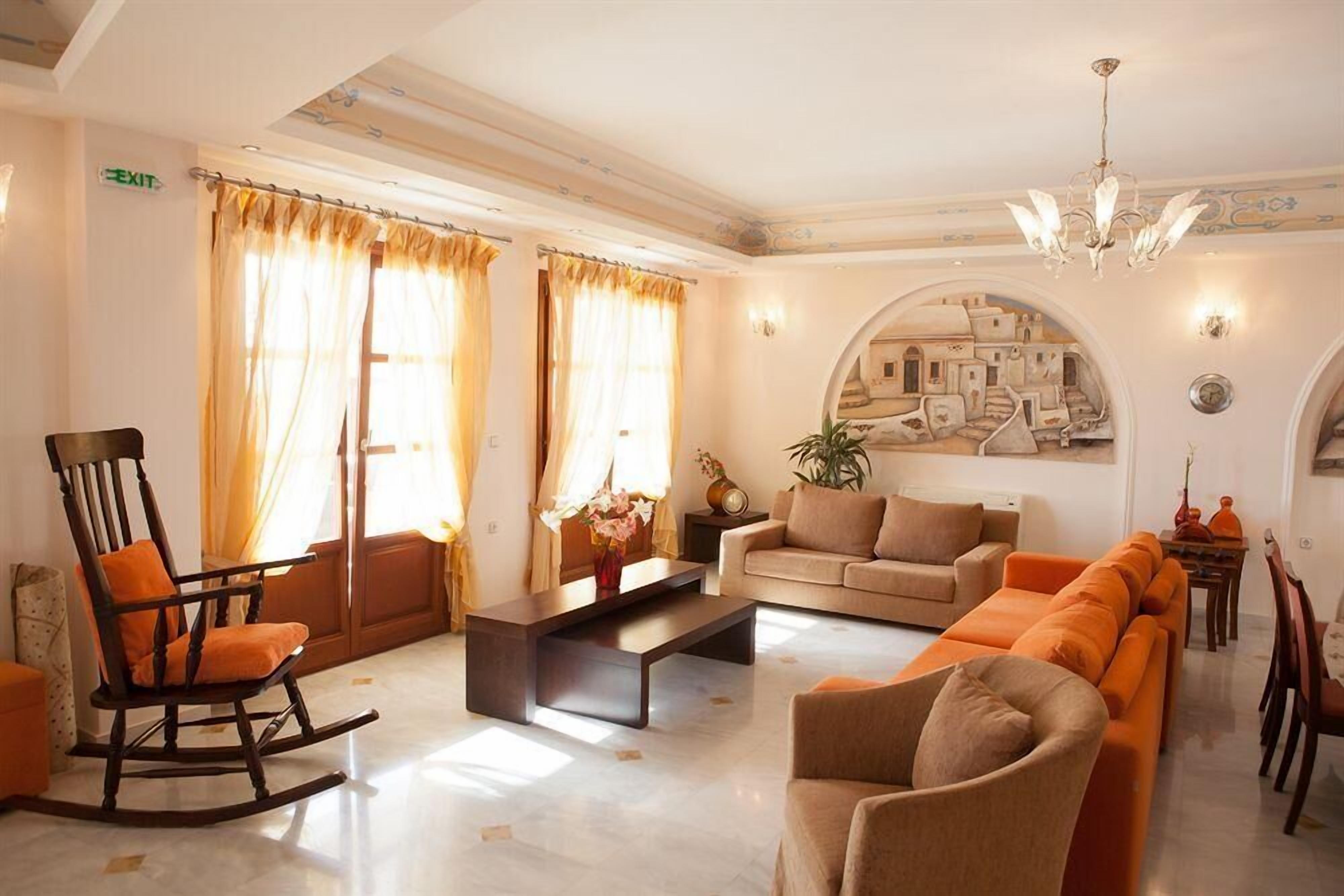 A living room with a sofa, a rocking chair, a coffee table, and a painting of a cityscape.
