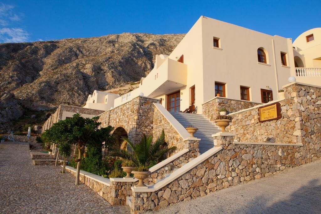 A building with a stone facade, a staircase leading to a door, and a mountainous backdrop.