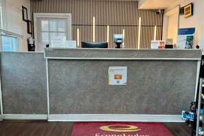 A reception desk with a sign indicating pet fees, a welcome mat, and a wall-mounted clock.