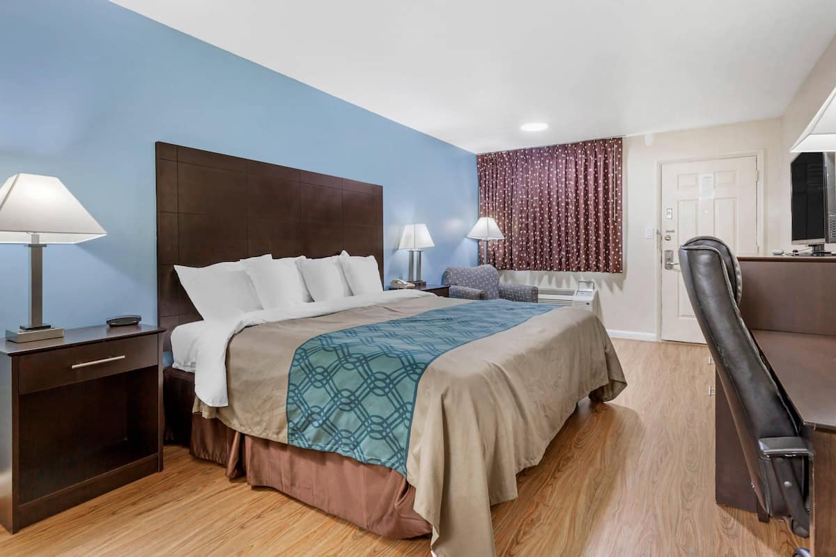 Ein Hotelzimmer mit Bett, Nachttischen, Schreibtisch und Stuhl.