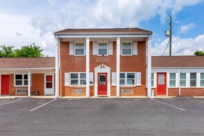 A two-story building with a red door, multiple windows, and a parking lot in front. - Econo Lodge Woodstock - Shenandoah Valley I-81 (Woodstock)