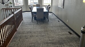 A conference room with a long table, four chairs, and a high ceiling.