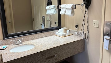 A hotel bathroom with a sink, mirror, towel rack, and hair dryer.
