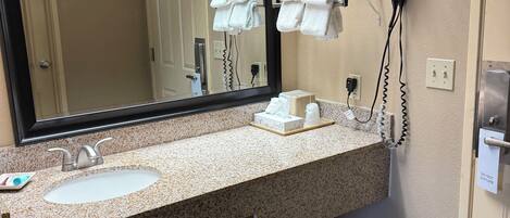 A hotel bathroom with a sink, mirror, towel rack, and hair dryer.
