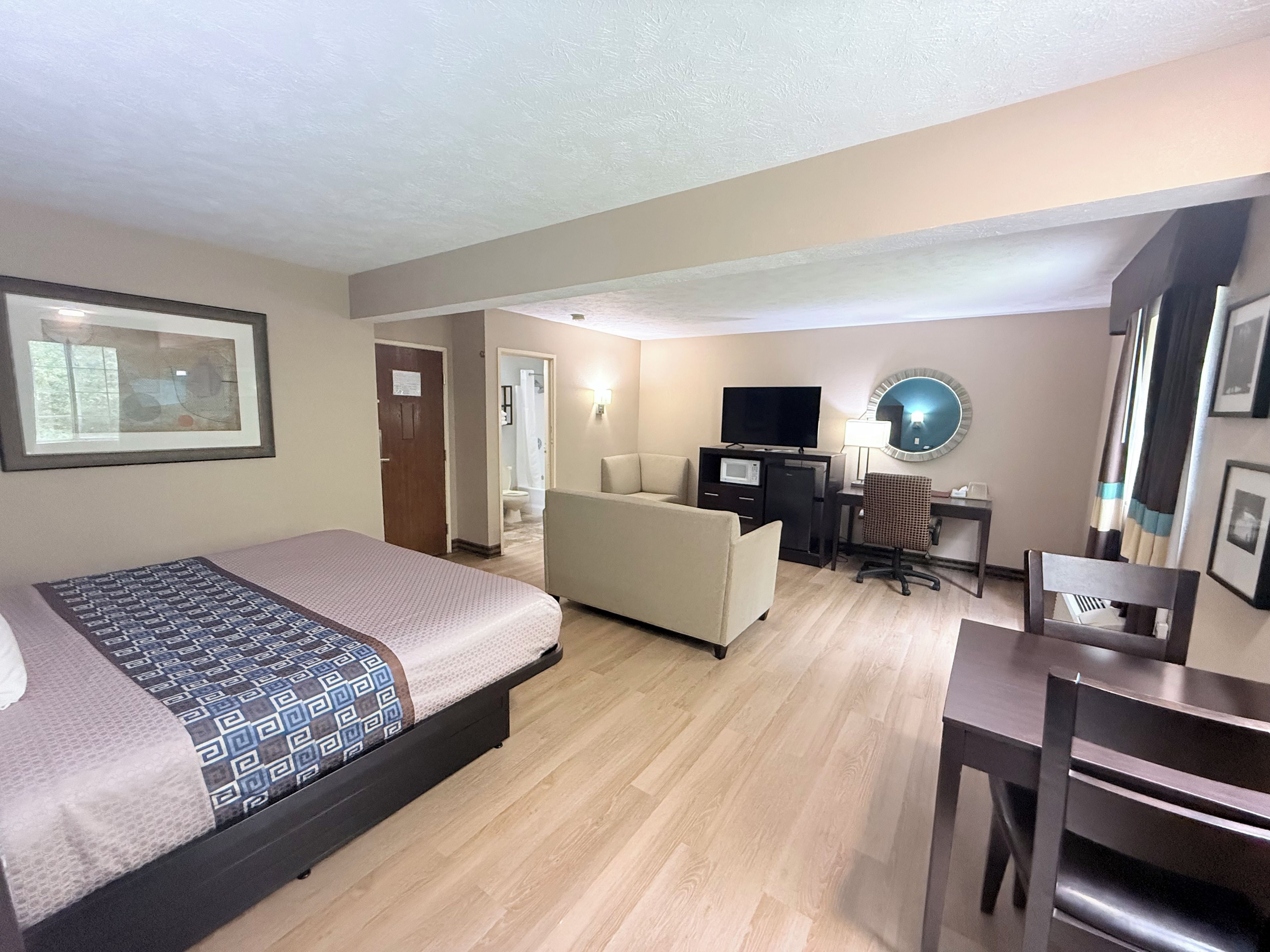 Une chambre d’hôtel comprenant un lit, un bureau, une chaise, une télévision et un miroir.