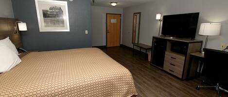 A hotel room with a large bed, a desk with a computer, a TV, and a mirror.