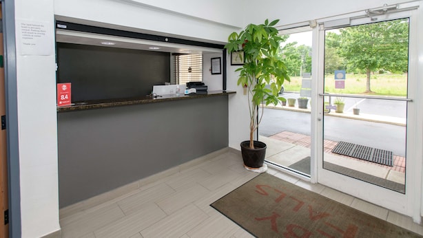 A reception area with a reception desk, a potted plant, and a door leading outside. - Home Town Inn Ringgold (Ringgold)