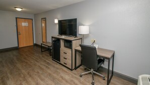 A hotel room with a wooden desk, a computer, a chair, a microwave, and a TV. - Home Town Inn Ringgold (Ringgold)