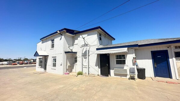 A two-story building with a blue door, a small porch, and a clear sky.