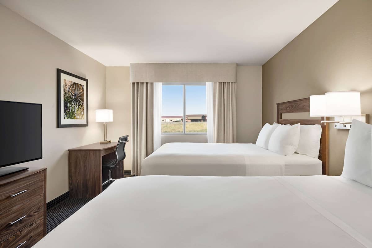 A hotel room with a bed, a desk, a chair, a television, and a window with curtains.