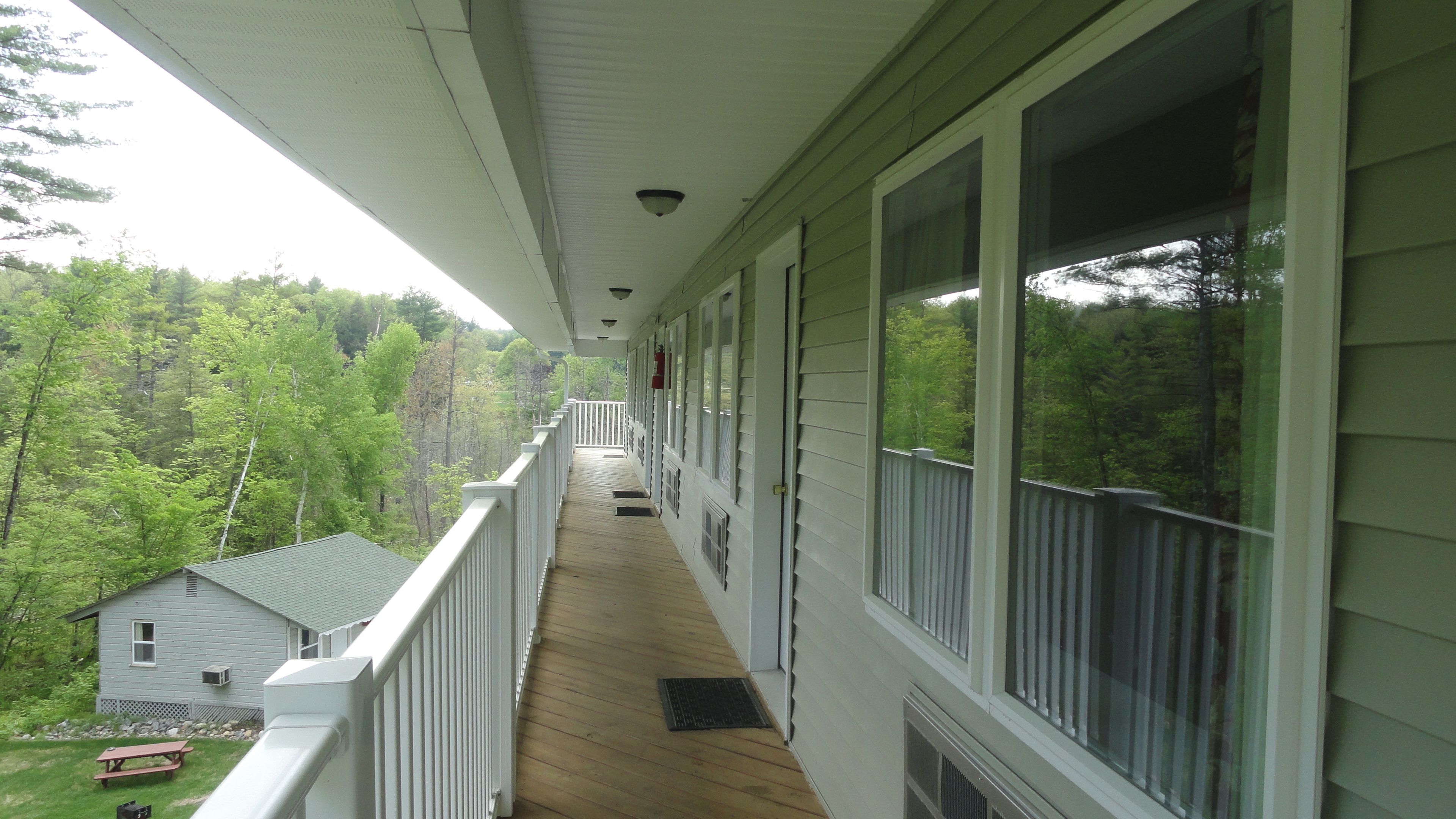 A covered porch with a view of a forested area.